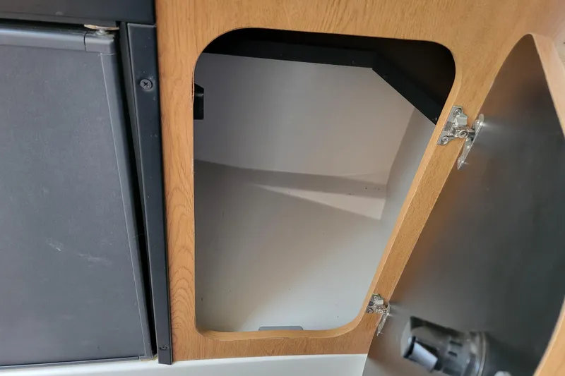 Slide: The Image of Open wooden cabinet door in 2007 Stingray 250 CS boat interior. - 28