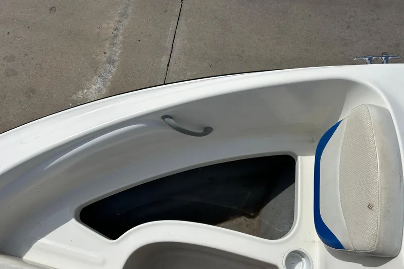 Slide: The Image of 2007 Bayliner 175 boat interior with white and blue seating, docked on concrete. - 13