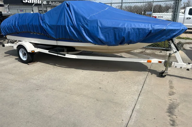 Slide: The Image of 2007 Bayliner 175 boat covered with blue tarp on trailer in parking lot. - 5