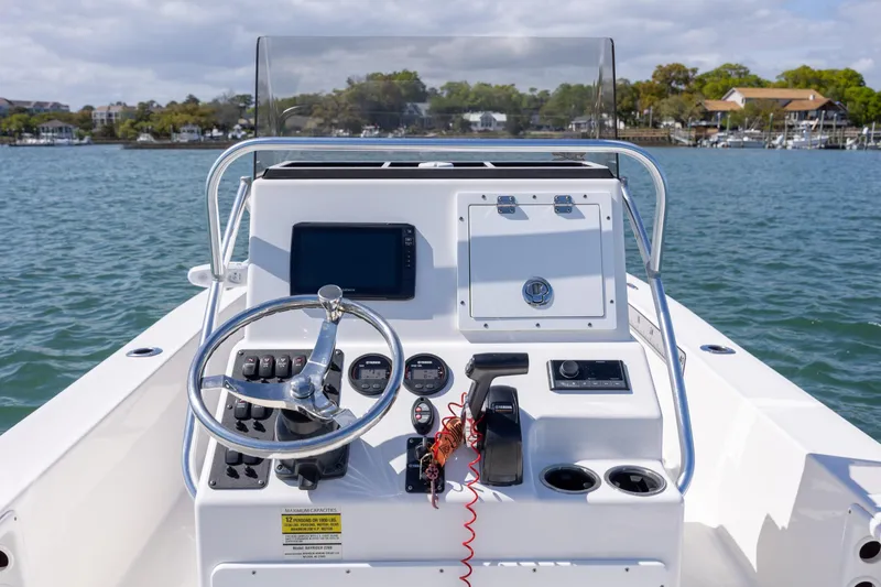 Slide: The Image of 2022 Bay Rider 2260 Skiff boat console with steering wheel and controls on water. - 11