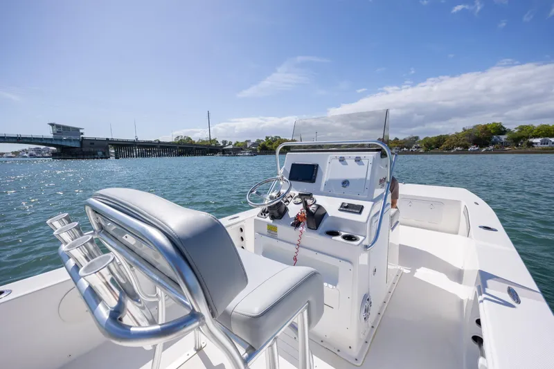 Slide: The Image of 2022 Bay Rider 2260 Skiff on water, featuring console and seating, near a bridge. - 12