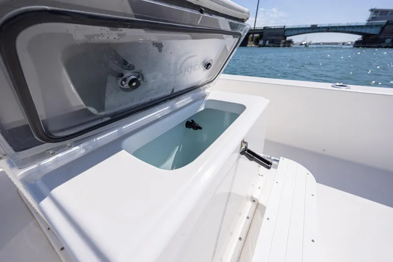 Slide: The Image of Bay Rider 2260 Skiff 2022 boat with open storage compartment, near a bridge on the water. - 16