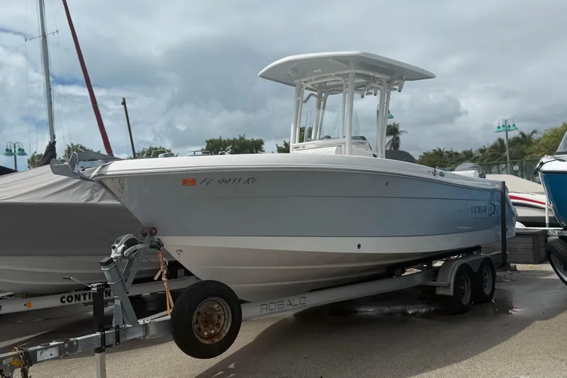 The Image of 2019 Robalo R242 Center Console boat on trailer, parked outdoors under cloudy sky. - 0