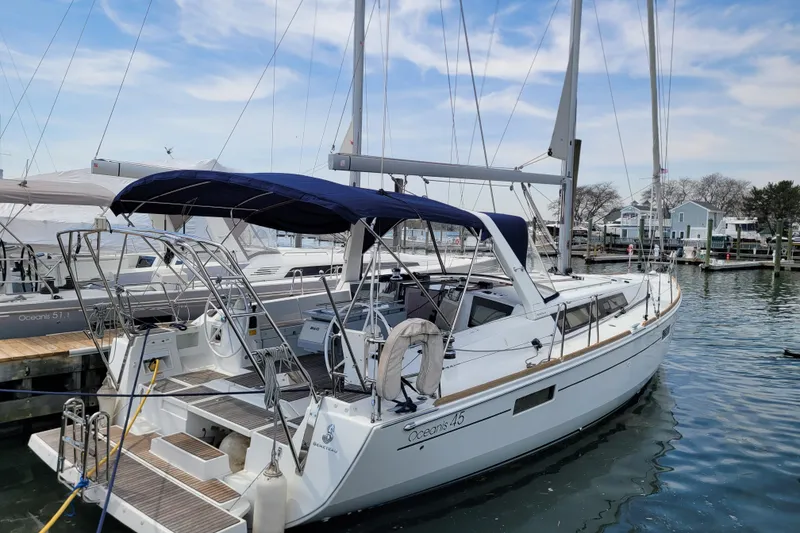 The Image of 2015 Beneteau Oceanis 45 sailboat docked in a marina under a blue sky. - 0
