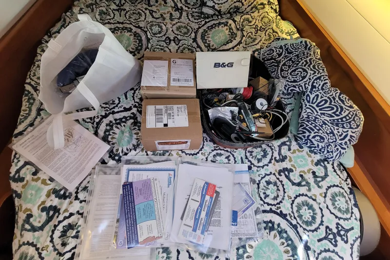 Slide: The Image of Assorted boating supplies and documents on a patterned bedspread in a Beneteau Oceanis 45 yacht. - 53