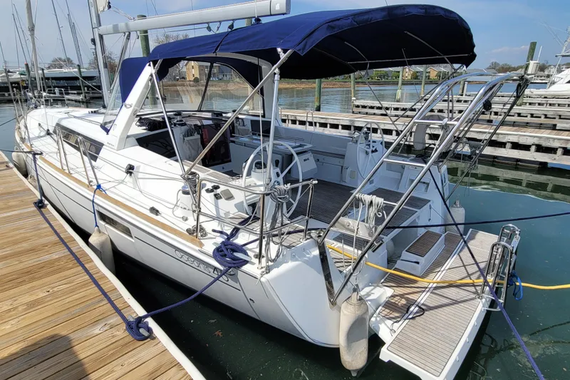 Slide: The Image of 2015 Beneteau Oceanis 45 sailboat docked, featuring a spacious cockpit and blue canopy. - 7