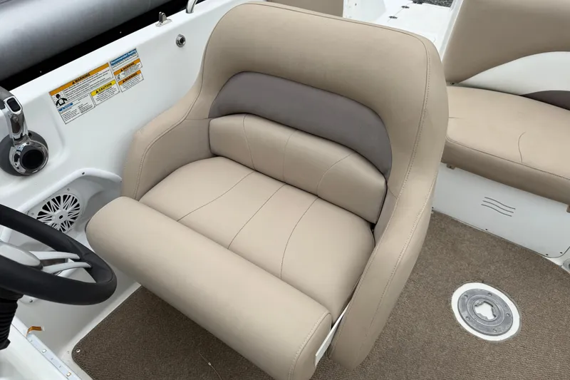 Slide: The Image of 2016 Hurricane SunDeck Sport 202 OB boat interior with beige captain's chair and steering wheel. - 15