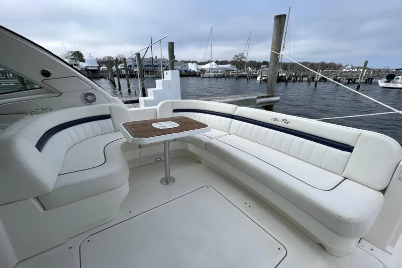 Slide: The Image of 2009 Sea Ray 480 Sundancer yacht interior with white seating and wooden table, docked at marina. - 5