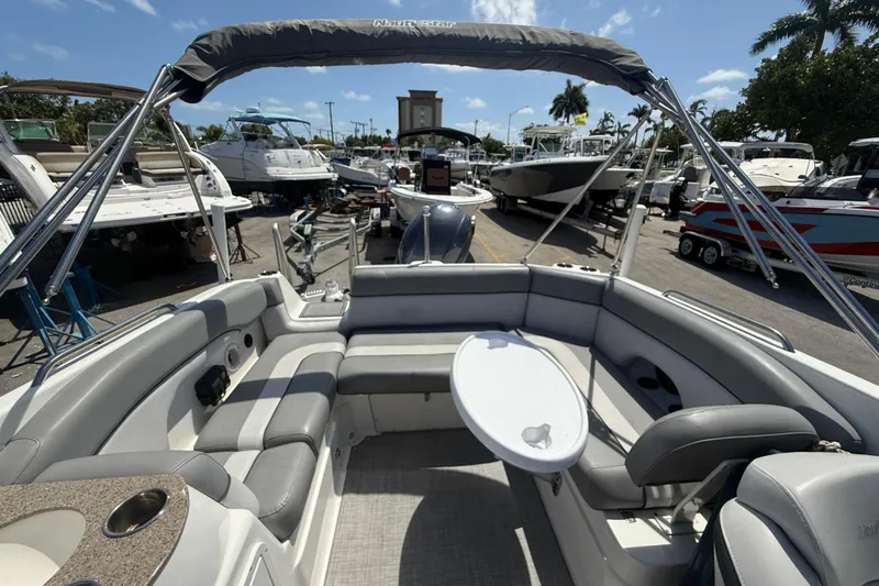 Slide: The Image of 2021 NauticStar 243DC Sport Deck boat interior with seating and table, docked at marina. - 7