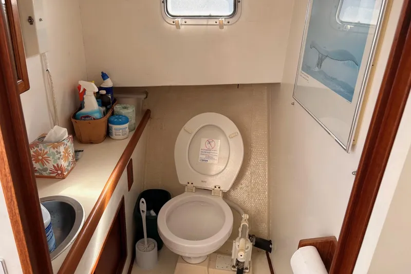 Slide: The Image of Compact boat bathroom with toilet, sink, cleaning supplies, and a whale poster, in a 1980 Custom Chesapeake. - 15