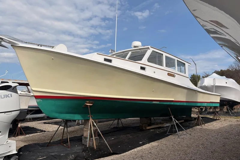 Slide: The Image of Custom 1980 Chesapeake boat on stands, featuring a cream and green hull, docked outdoors. - 2