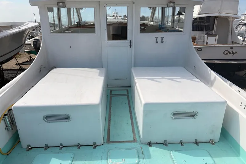 Slide: The Image of Custom 1980 Chesapeake boat interior with white seating and turquoise flooring at a marina. - 5