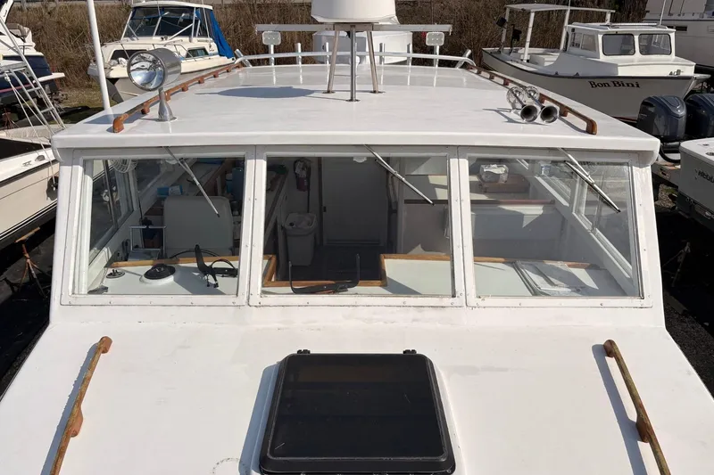 Slide: The Image of 1980 Custom Chesapeake boat with white cabin and multiple windows, docked among other vessels. - 8