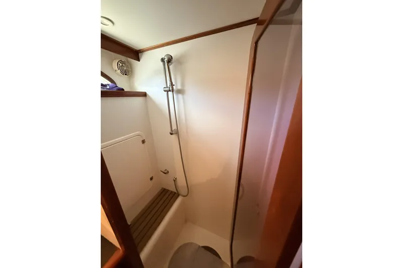 Slide: The Image of Shower area in a 2003 Mikelson Sportfisher boat, featuring wooden accents and modern fixtures. - 18