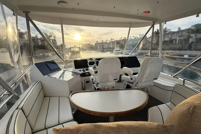 Slide: The Image of Interior of a 2003 Mikelson Sportfisher yacht with helm and seating area at sunset. - 19