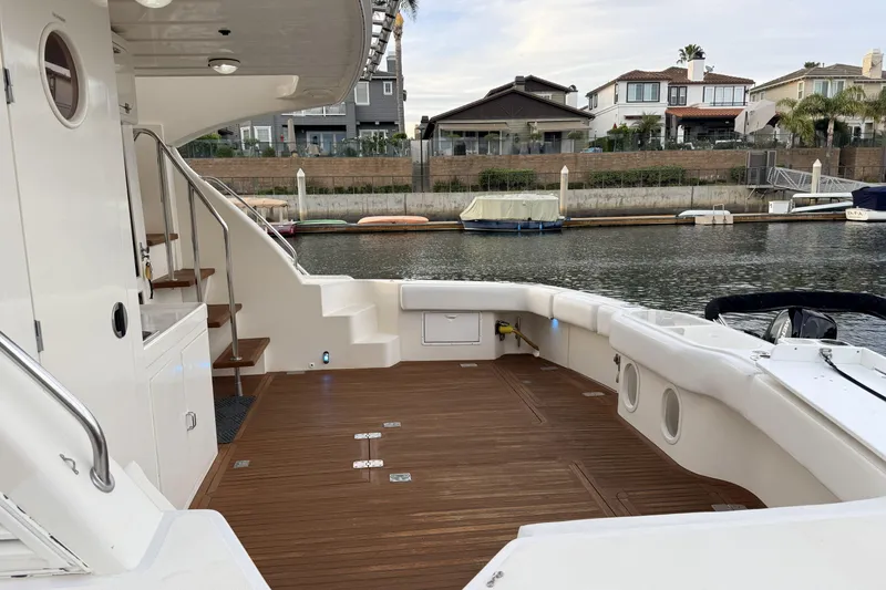 Slide: The Image of 2003 Mikelson Sportfisher yacht deck with wooden flooring, docked near waterfront homes. - 2