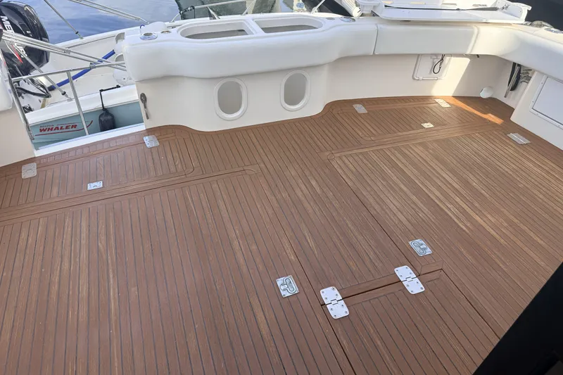 Slide: The Image of 2003 Mikelson Sportfisher boat deck with teak flooring and storage hatches. - 5
