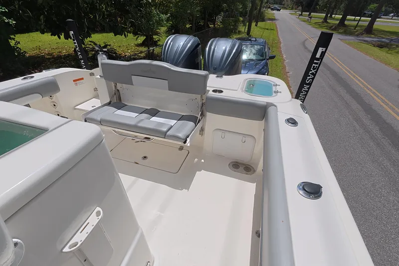 Slide: The Image of 2021 NauticStar 28 XS boat interior with seating and dual engines, parked on roadside. - 10