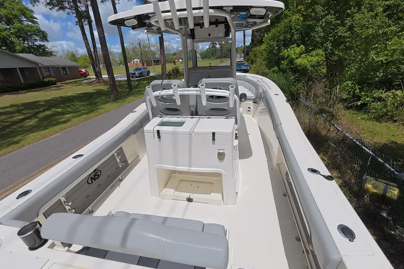 Slide: The Image of 2021 NauticStar 28 XS boat interior with seating and console, parked on a sunny day. - 11