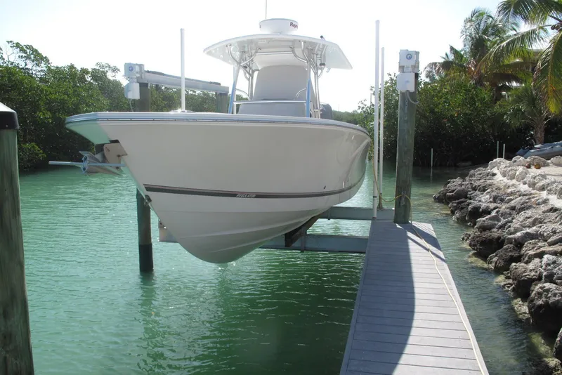 Slide: The Image of 2013 Regulator 32 Forward Seating boat on lift in tropical marina setting. - 1