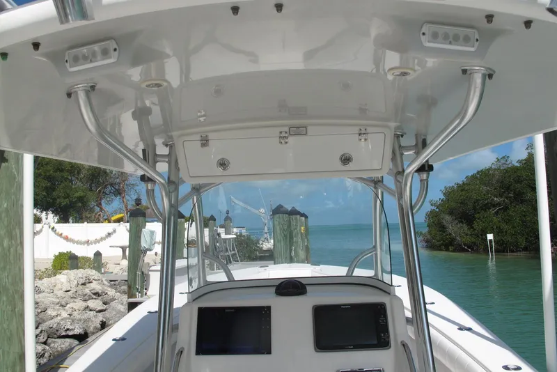 Slide: The Image of 2013 Regulator 32 Forward Seating boat console with electronics, docked by clear water and greenery. - 12