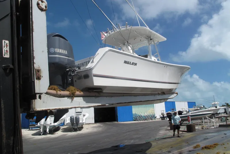 Slide: The Image of 2013 Regulator 32 Forward Seating boat lifted by crane at marina. - 31