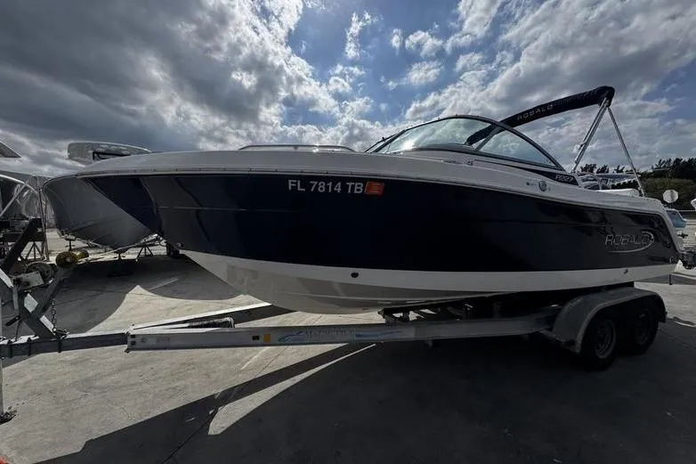 Slide: The Image of 2021 Robalo R227 Dual Console boat on trailer under cloudy sky. - 2