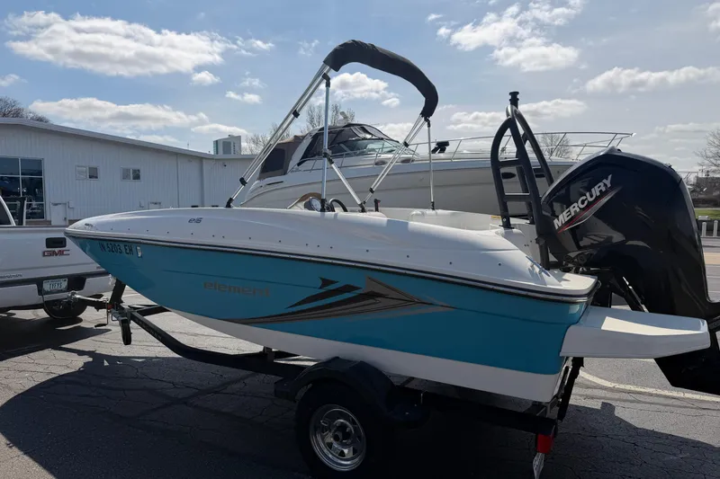 Slide: The Image of 2021 Bayliner Element E16 boat with Mercury engine on trailer, parked outdoors. - 16
