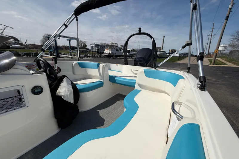 Slide: The Image of 2021 Bayliner Element E16 boat interior with blue and white seating, docked outdoors. - 18