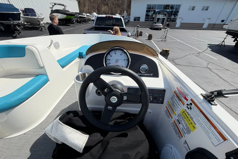 Slide: The Image of 2021 Bayliner Element E16 boat dashboard with steering wheel and gauges in a parking lot. - 21