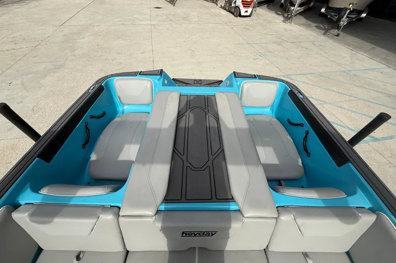 Slide: The Image of 2023 Heyday WT-2DC boat interior with blue and gray seating, docked outdoors. - 15