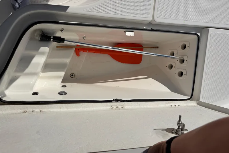 Slide: The Image of Open storage compartment on 2017 Epic 23 Sport Console boat with cleaning tools inside. - 11