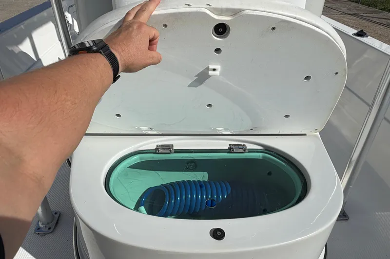 Slide: The Image of Open hatch on 2017 Epic 23 Sport Console boat showing storage compartment with coiled hose. - 13