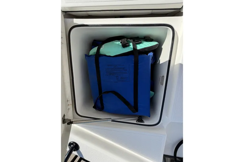Slide: The Image of Storage compartment on 2017 Epic 23 Sport Console boat with life jackets inside. - 22
