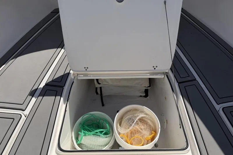 Slide: The Image of Open storage compartment on 2004 Fountain Bluewater 34 CC boat with buckets and nets. - 19