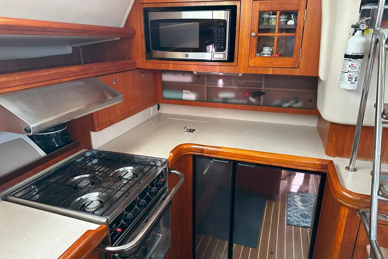 Slide: The Image of Galley kitchen in 2006 Hunter 45 CC sailboat with stove, microwave, and wooden cabinetry. - 25