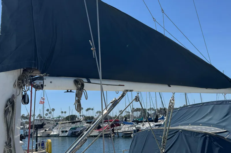 Slide: The Image of 1989 Ericson Sloop sailboat with covered boom, docked in a marina under clear skies. - 2