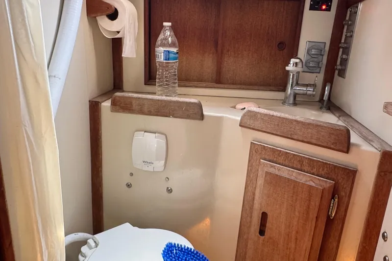 Slide: The Image of 1989 Ericson Sloop bathroom with sink, toilet, and wooden cabinetry. - 34