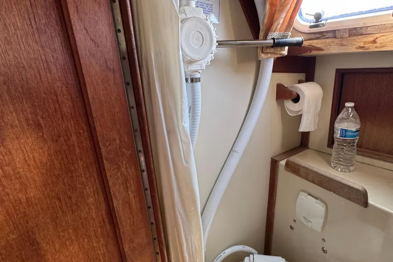 Slide: The Image of Interior of 1989 Ericson Sloop bathroom with pump, toilet paper, and water bottle. - 35