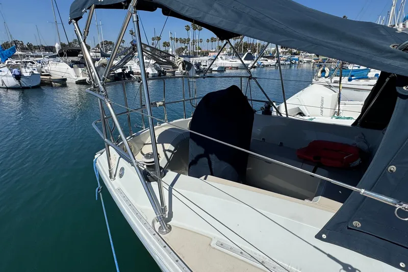 Slide: The Image of 1989 Ericson Sloop sailboat docked in marina, featuring covered cockpit and clear blue water. - 6