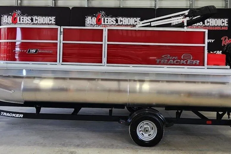 The Image of 2026 Sun Tracker Party Barge 16 DLX pontoon boat on trailer in showroom. - 1