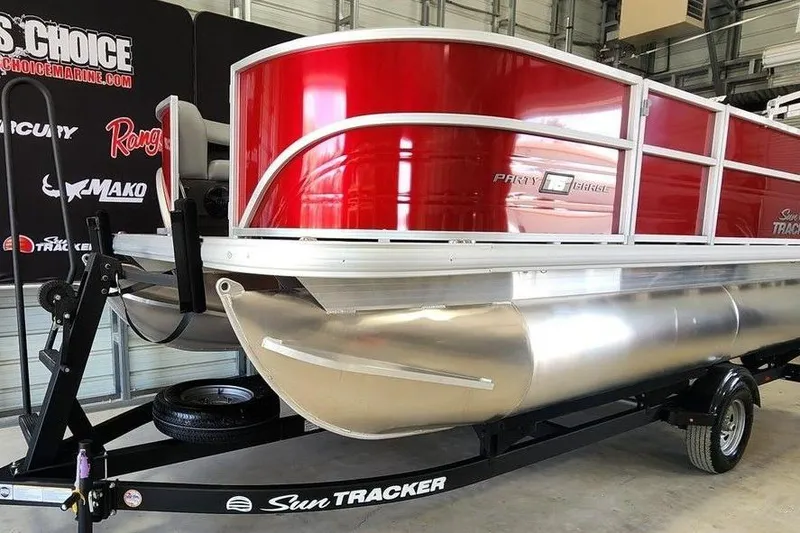 Slide: The Image of 2026 Sun Tracker Party Barge 16 DLX pontoon boat in showroom, featuring red and silver design. - 8