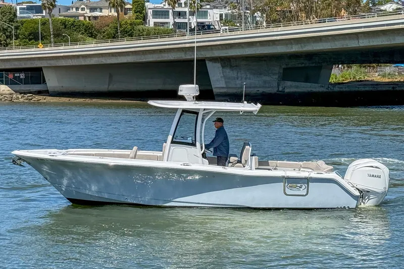 The Image of 2025 Sea Hunt Ultra 275 SE boat cruising under a bridge on a sunny day. - 0