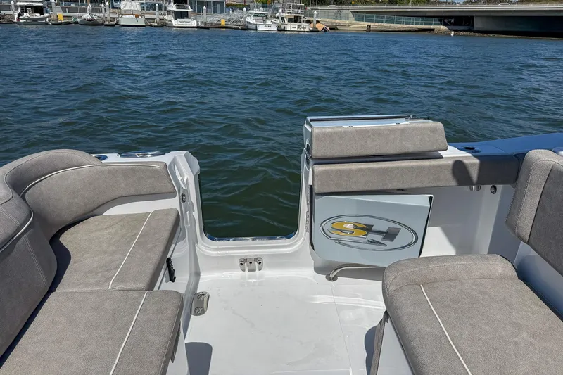 Slide: The Image of 2025 Sea Hunt Ultra 275 SE boat interior with cushioned seating, docked by the water. - 12
