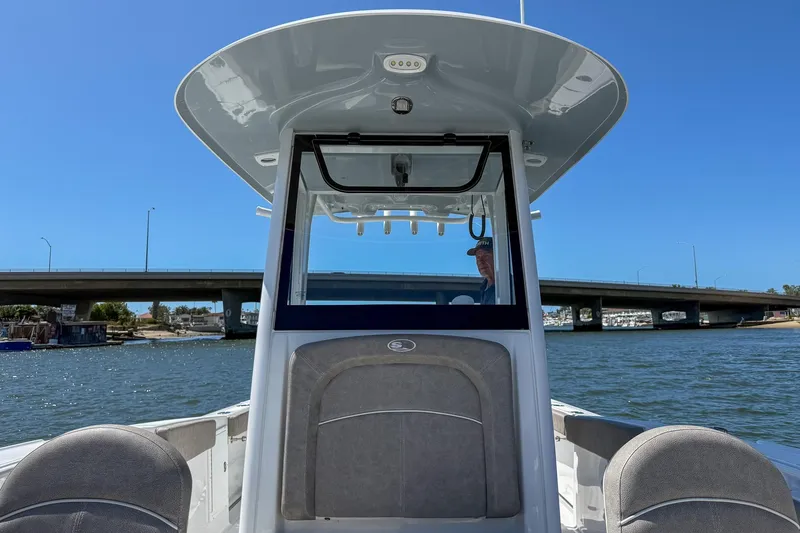 Slide: The Image of 2025 Sea Hunt Ultra 275 SE boat on water near a bridge, clear blue sky. - 17