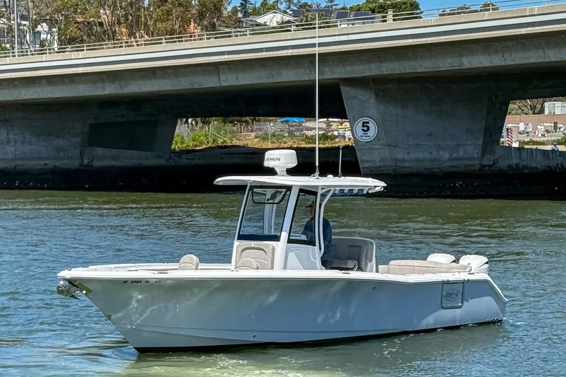 Slide: The Image of 2025 Sea Hunt Ultra 275 SE boat cruising under a bridge on a sunny day. - 2