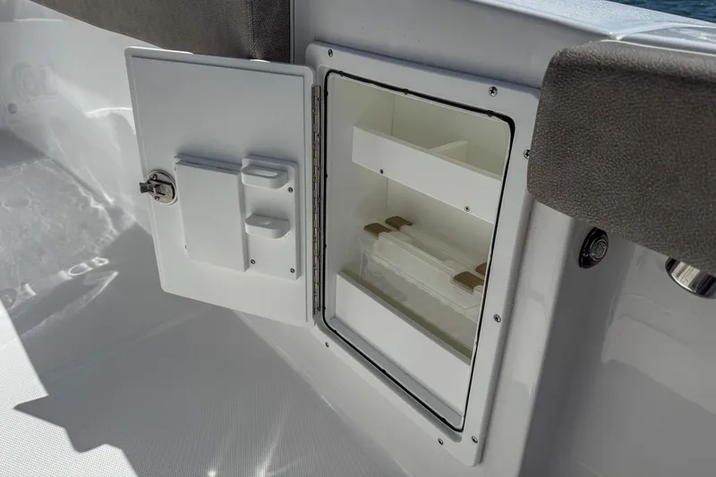Slide: The Image of Storage compartment on 2025 Sea Hunt Ultra 275 SE boat, featuring open door and organized interior shelves. - 47