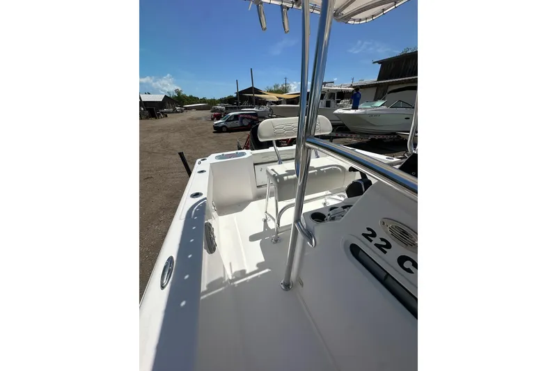 Slide: The Image of 2023 LFG 22 CC boat interior with seating and console, parked outdoors. - 21