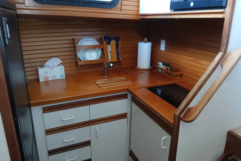 Slide: The Image of Compact kitchen area in a 1988 Carver 36 Command Bridge boat, featuring wooden cabinetry and modern appliances. - 5