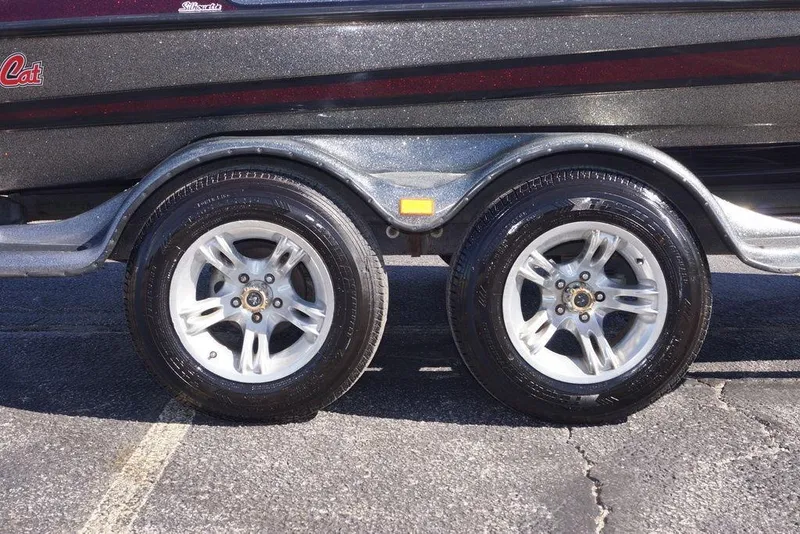 Slide: The Image of 2010 Bass Cat Cougar trailer with shiny dual wheels on asphalt. - 10
